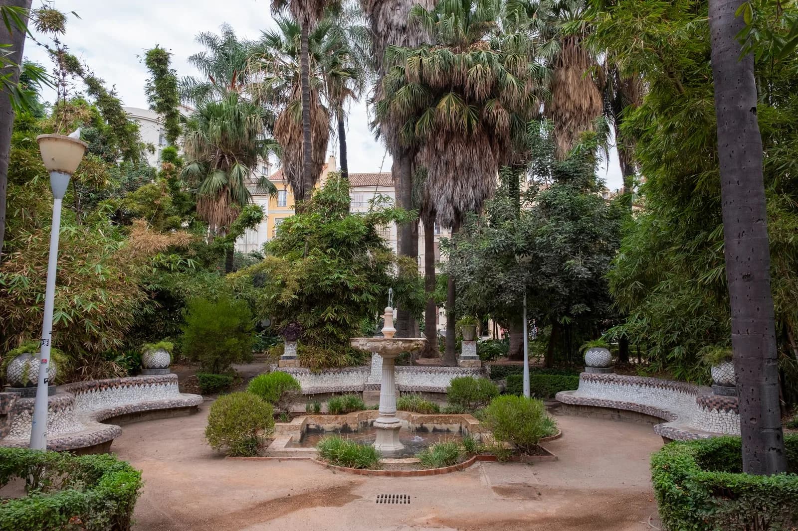 Jardin méditerranéen avec palmiers, fontaine centrale et bancs en pierre