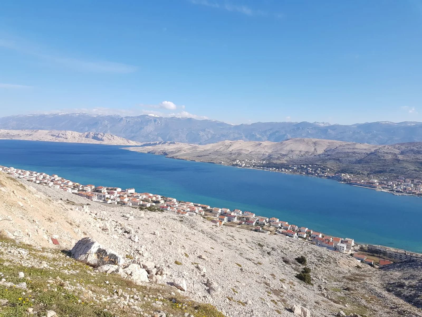 La baie de Pag, ses versants de pierre blanche et le massif du Velebit enneigé en arrière-plan