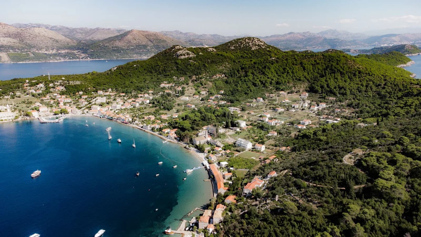 Vue aérienne d'une baie bordée de pinèdes et de maisons à toits orange, sur la côte de Dalmatie près de Cavtat