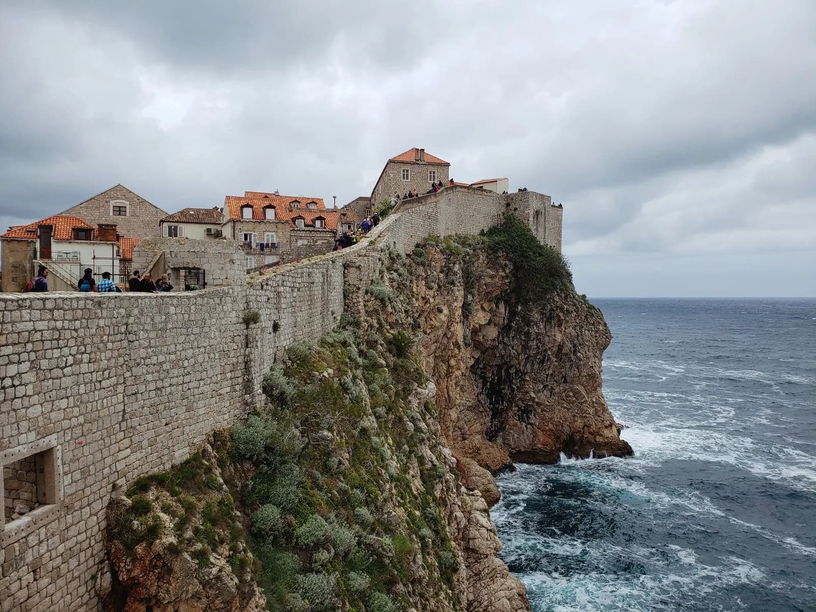 Le mur côté mer des remparts de Dubrovnik, long mur de pierre au-dessus de la falaise et de l'Adriatique agitée