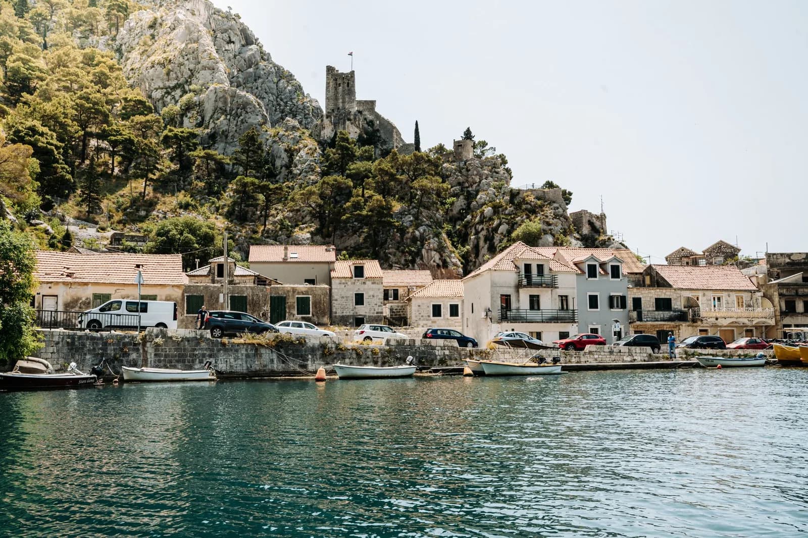 Front de mer d'Omiš au bord de la Cetina, avec une tour de pierre sur la colline au-dessus des maisons