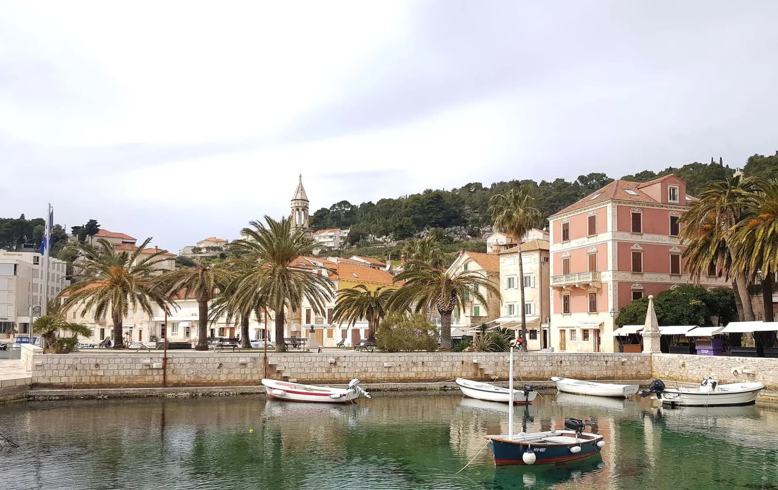 Le front de mer de la ville de Hvar bordé de palmiers, avec ses barques de pêche