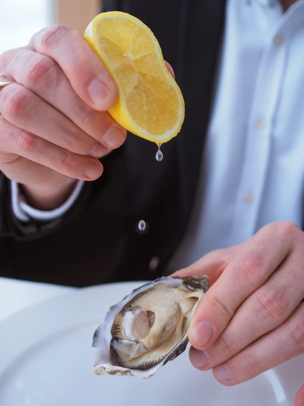 Une huître ouverte arrosée d'un jus de citron