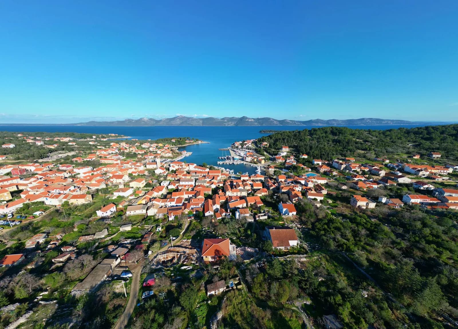 Vue aérienne de Mali Lošinj, ses toits orange et ses pins au bord de la mer, dans le Kvarner