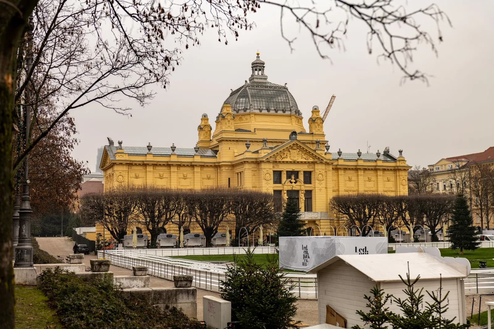 Le pavillon d'art de Zagreb et la patinoire installée devant lui pendant l'Avent, sous un ciel d'hiver couvert, en Croatie