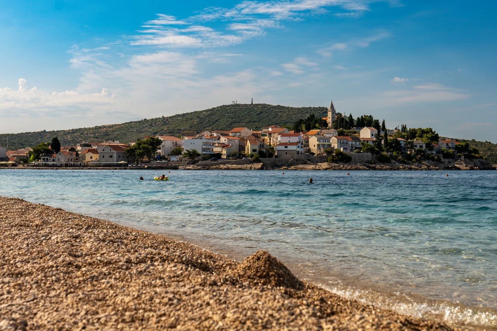 Plage de galets de Primošten avec la vieille ville et son clocher en arrière-plan
