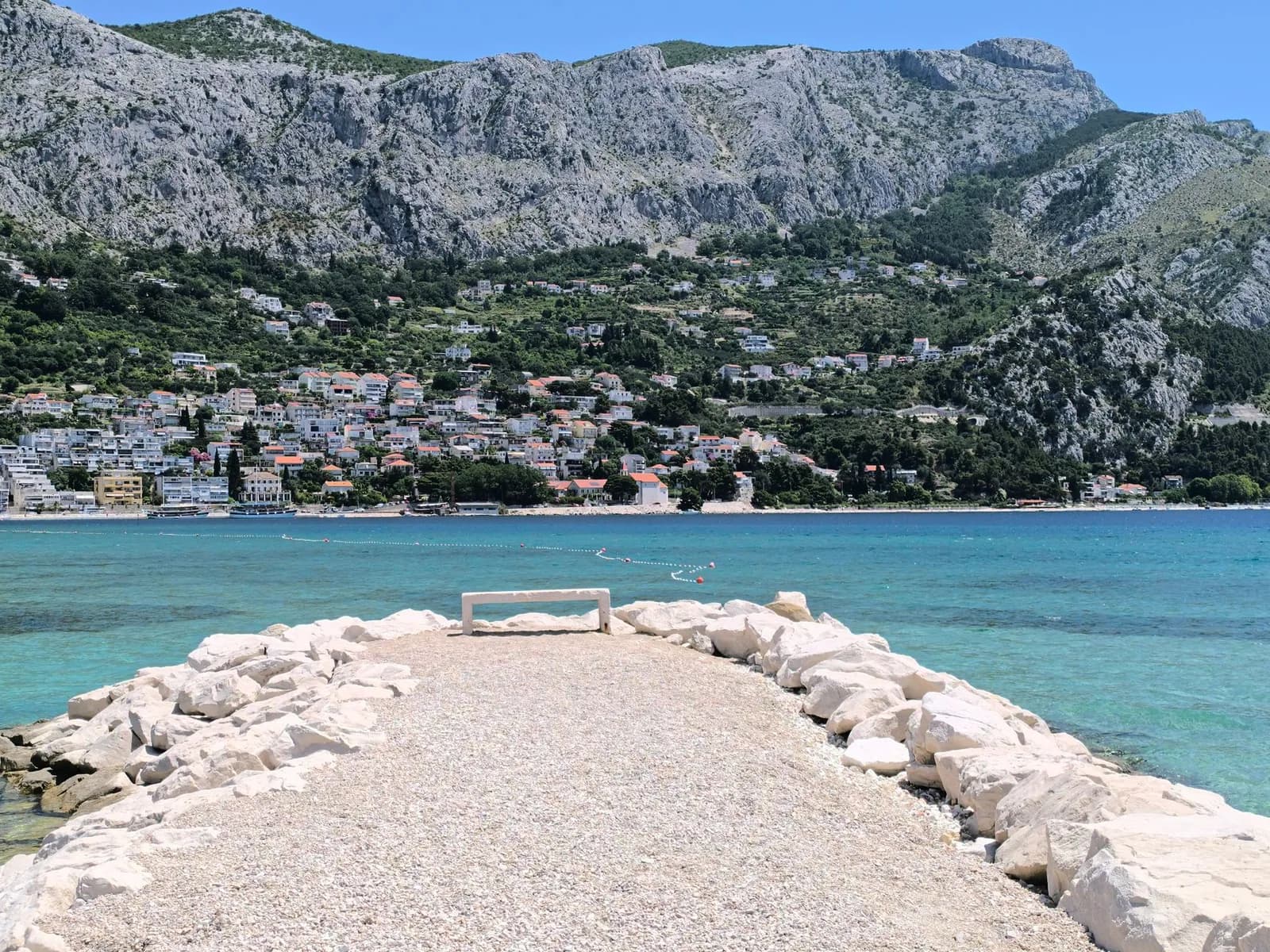 Jetée de galets et de blocs blancs devant la côte d'Omiš et la montagne qui la domine