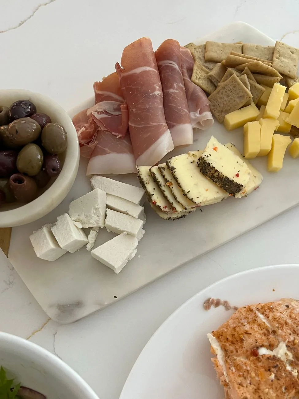 Des tranches fines de jambon sec sur une planche avec du fromage et des olives