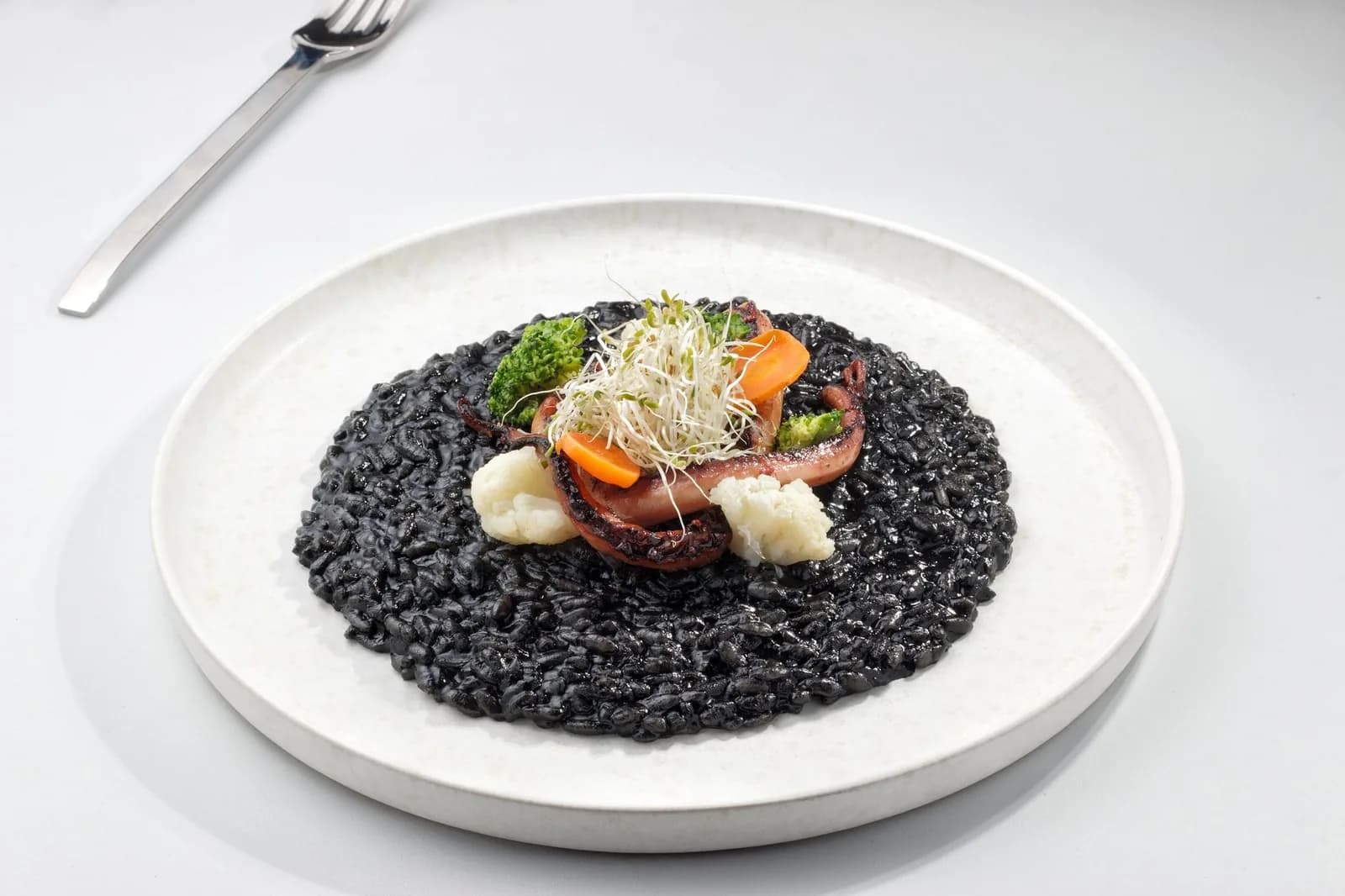 Un risotto noir à l'encre de seiche dans une assiette blanche