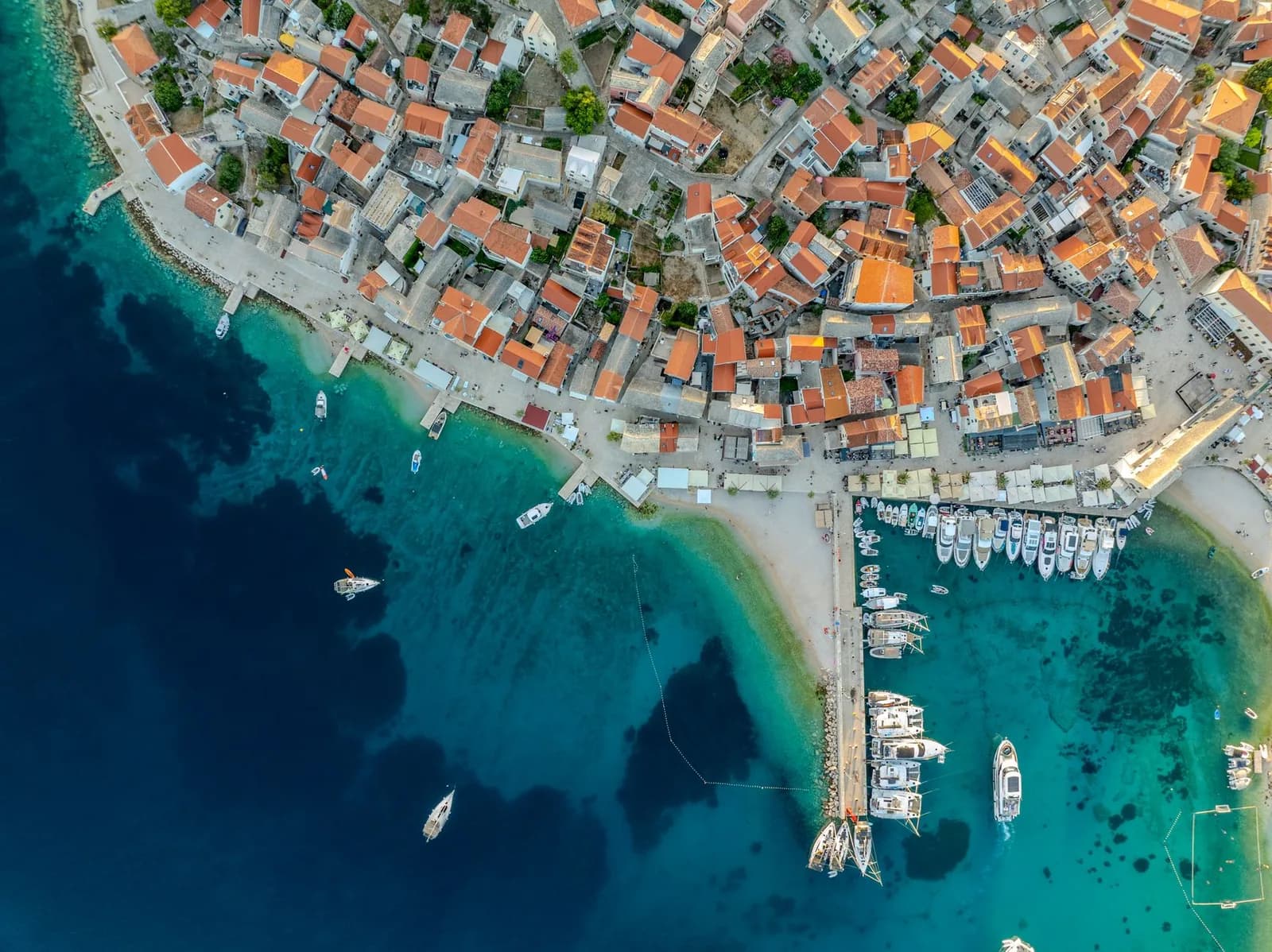 Toits de tuiles et maisons de pierre de la vieille ville de Primošten au-dessus du port et de l'eau turquoise