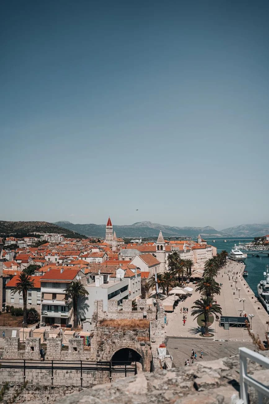 Les toits de tuiles de la vieille ville de Trogir, le clocher de la cathédrale et la Riva bordée de palmiers