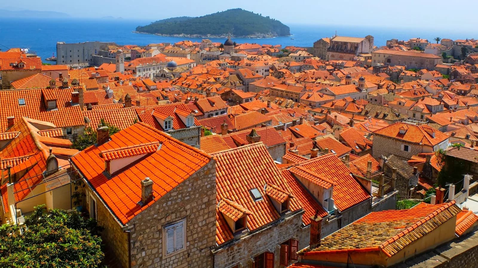 Toits orange de la vieille ville de Dubrovnik vus d'en haut, avec l'île de Lokrum et la mer Adriatique au fond
